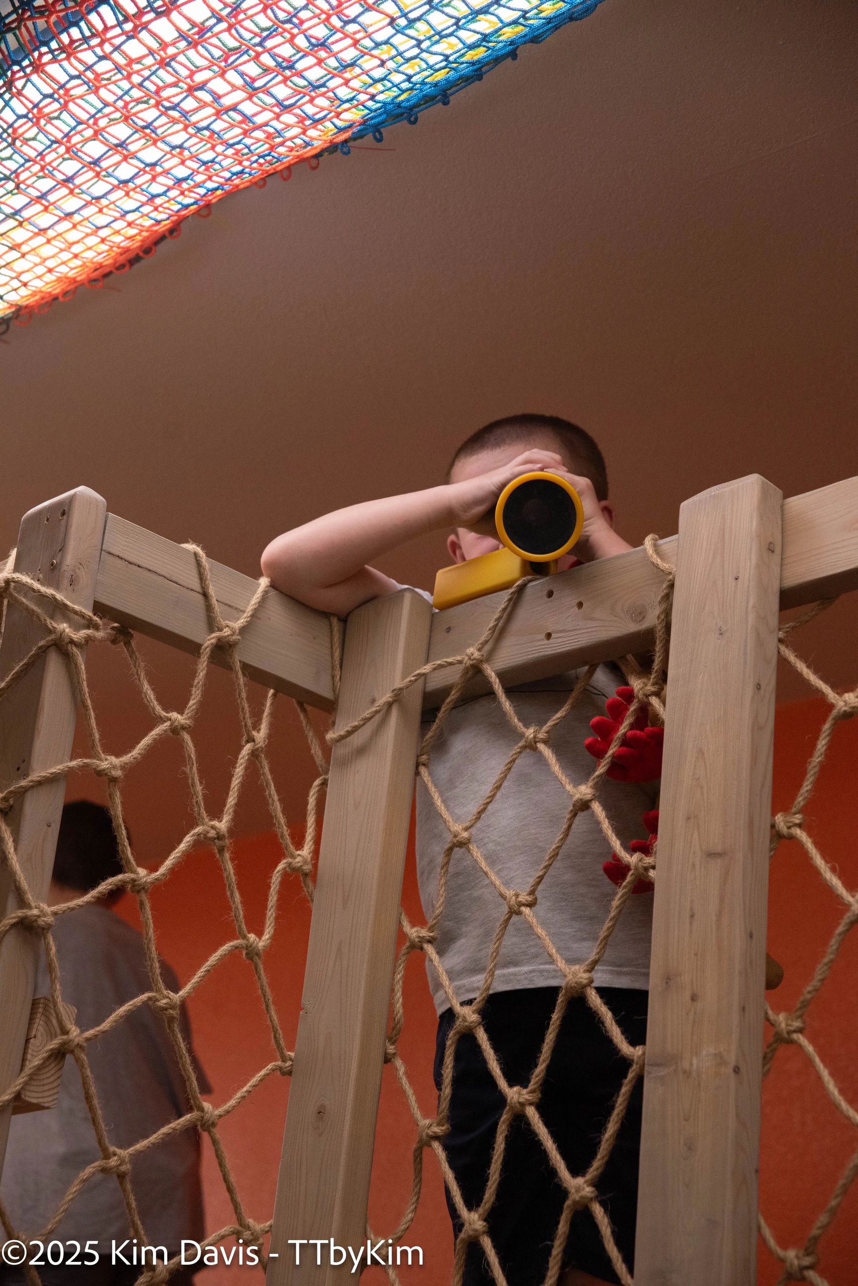Child using binoculars on play structure